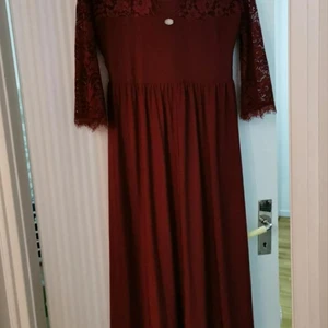 Fest klänning storlek L - En lång vinröd fest klänning som är halvt långärmad med spets på. På bilden ser ni både framsidan och baksidan av klänningen, på baksidan är det en öppning. Klänningen är använd bara en gång och den är köpt 2020 från Bubbleroom. Jag säljer den eftersom att den bara står i garderoben utan att jag använder den.  Storlek L  Jag köpte den för 800 kr