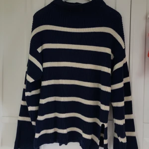 Stickad tröja - En marinblå tröja med vita ränder. Tröjan har en lös krage och utsvängda armar💕