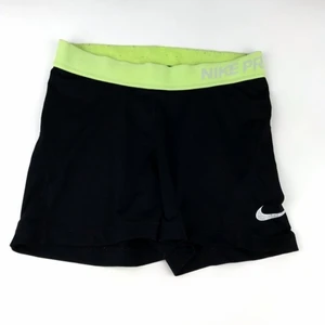 Nike PRO shorts - Snygga svarta Nike PRO shorts med gul/gröna detaljer. Super snygga och i bra skick men har tyvärr blivit för små. Frakt ingår i priset