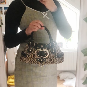 Guess väska - Säljer min fina vintage Guess väska, köpt second hand. Är i jätte bra skick med några små skrapor (I bild 3 finns det en liten fläk markerad). Dustbag medföljer. BUDDGIVING på varan!💗
