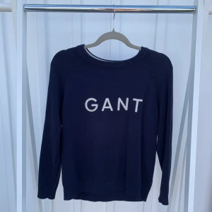 Marinblå tröja från GANT - En lite tunnare stickad tröja från GANT i marinblå färg som har märket broderat i vitt på bröstet. Jag skulle tippa på storlek S/M men vet inte helt säkert pågrund av avklippt lapp.