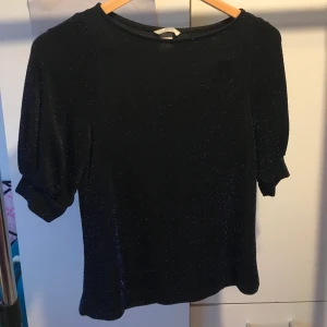 Glittrig mörkblå tröja - Glittrig mörkblå tröja. Glittret går inte av utan är som små fasta stenar. Använd endast en gång. Lite för stor för mig. Passar S och M. Nypris 170kr.