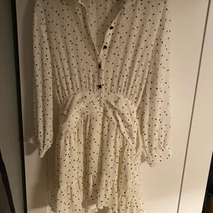 Zara klänning - Såå fin klänning med volang längst ner, köptes på Zara den här sommaren. Vit med små svarta prickar på. Snygg detalj i midjan. Använd vid bara ett tillfälle.