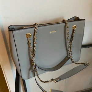 Grå axelremsväska från DKNY - Denna fina gråa axelremsväska från DKNY har jag haft några år men bara använt ett fåtal gånger. Den är i super bra skick och har en tillhörande dustbag. Priset är exklusive frakt. Ord pris 2500 kr! 