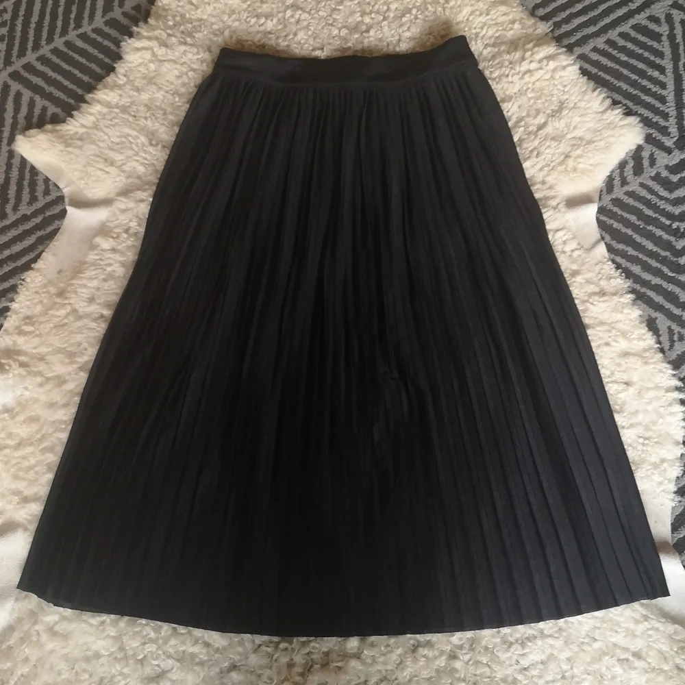 En fin plisserad svart kjol med dragkedja och och knapp på sidan. Fint fall och snygg passform. Fint skick! . . Kjolar.