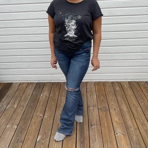 T-shirt med tryck  - T-shirt från H&M med ett coolt tryck. På trycket är det Bowie och sedan glittriga guld stjärnor. Färgen är i tvättad mörk grå. Storlek XL men passar även M/L också, (modellen på bilden bär S-L). Skicket på tröjan är mycket bra då den är använd fåtal gånger. 50kr + frakt! 🖤