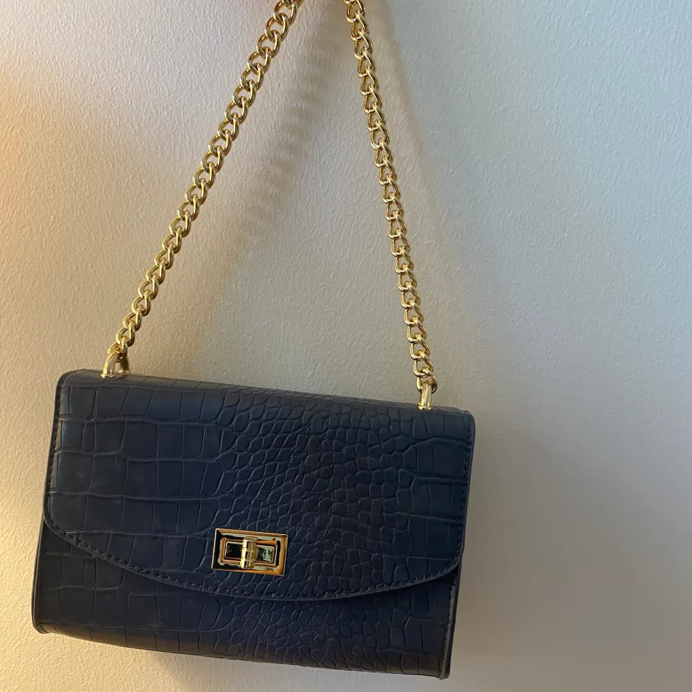 En super snygg blå väska från NAKD med gulddetaljer. Väskan har bara använts en gång och axelbandet är fortfarande oöppnat. Det ser ut som att det är fläckar men jag fick väska så ( ni kan se på bild 2) inget man märker💞. Accessoarer.