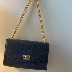 Snygg väska  - En super snygg blå väska från NAKD med gulddetaljer. Väskan har bara använts en gång och axelbandet är fortfarande oöppnat. Det ser ut som att det är fläckar men jag fick väska så ( ni kan se på bild 2) inget man märker💞