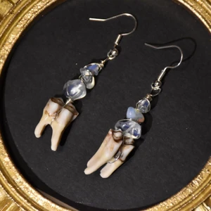 Örhänge tänder  - Örhängen med äkta tänder från rådjur och opalite. Krokarna är nickelfria. Finns endast ett par!! 