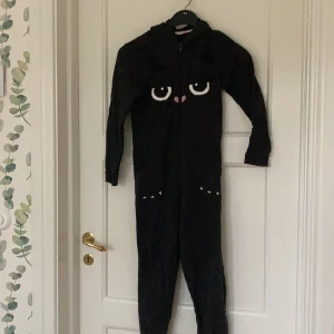 Katt onepiece - Jag säljer en mysig onepiece med kattögon och öron på luvan. Den är i storlek 140/9-10 år och är använd ett fåtal gånger när jag var yngre. Jag kan mötas upp i Täby eller Danderyd, annars tillkommer frakt. Pris kan diskuteras.
