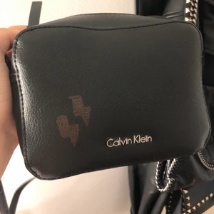 Calvin Klein väska  - Säljer denna lilla väskan som är super fin! Har målat ditt 2 blixtar på den⚡️, har även klippt av en bit av bandet (sista bilden) så att den blev rätt kort! Kan gå ner i pris vid snabb affär💓