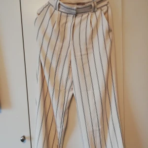 Randiga kostymbyxor storlek 38 - Randiga kostymbyxor från HM i storlek 38 men passar mer en 36. Kommer med ett band så att man kan få en paperbag waist i midjan. Använda cirka 3 gånger så de är i nyskick 