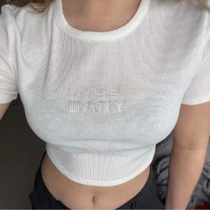 Vit crop top med texten ”Angel Baby” i silver glitter. Så fin att ha till vardags eller klä upp till lite festligare tillfällen✨ Köpt på Hm för ca två år sedan så troligtvis slutsåld. Lapp borttagen men tror det är M! 