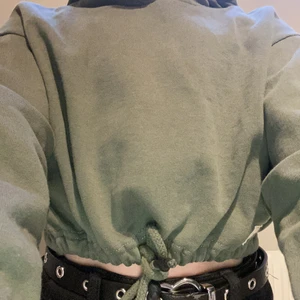 Topp i form av hoodie! - En topp i form av hoddie! Den är grön och har snören för att kunna knyta åt. Andvänt max 5ggr. Tröjan har även en luva. Denna tröja var förliten för mejj!