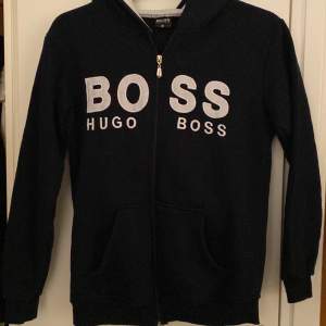 Hugo Boss kofta i storlek M. Kofta är svart men skiftar lite blått och har vita detaljer. Inte äkta!