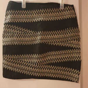 Cool minikjol  - Svart minikjol i elastiskt material. Mönstrad med vit sömnad framtill. Från H&M, storlek M. 42 cm lång framtill, 74 cm i midjan (omkrets).  Som oanvänd.   Köparen står för frakten. Plagget kan hämtas i Stockholm city eller nordöstra Stockholm.