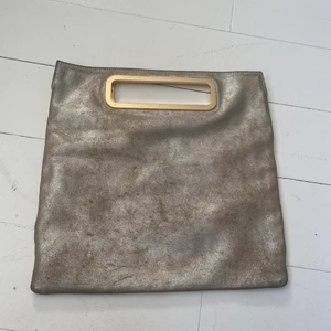 Fin handväska från Rizzo - I silverskinn med guldhandtag i påsmodell. Perfekt cool detalj såväl till vardags som på finare tillställning. Blir snyggare ju mer den används! 