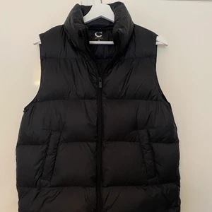 Svart dun väst - Säljer denna as snygga dun västen från Cubus. Den är helt slutsåld på hemsidan och är endast använd 2 gånger, så i nyskick.💜Storlek S och sitter lite oversize på mig som är cirka 160cm lång, men skulle passa både kortare och längre!😊 Jag köpte den ny för 700kr för cirka 1 månad sedan. Hör av er för fler bilder mm, buda själva!😁 Luva medföljer som man kan ta av och på! OBS: Skriv även privat om man lägger ett BUD!!