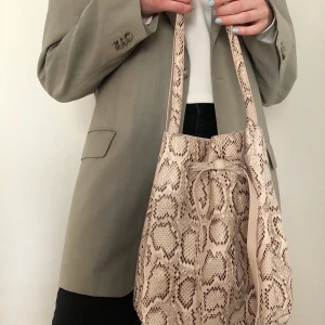 Beige snake väska - Snygg beige snake väska i skinnimitation, bra skick. Etiketter saknas så vet inte vilket märke det är. 