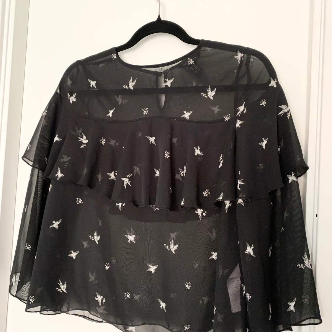 Svart blus med fågel motiv och volanger