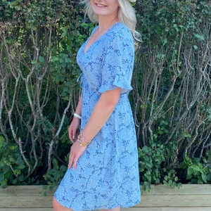 Blå klänning - Säljer denna somriga klänningen från NA-KD. Endast använd en gång, och i väldigt fint skick! V-ringad, med detaljer vid bröst/midja 🦋✨🌼