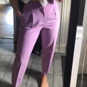 Lila byxor från Zara - Storlek M. 💜 Köpta förra året från Zara, använd endast en gång. Andra bilden är från zaras hemsida och det är samma byxa fast annan färg, byxan heter ”byxa med höj midja och skärp”. Det ingår också ett bredare skärp som syns på andra bilden! Kan mötas i Borås eller skicka 💜