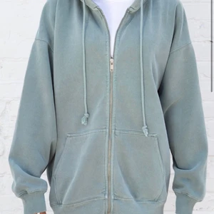 Christy hoddie, Brandy Melville  - Säljer min Brandy Melville zip hoddie i färgen green pastell. Köpt för 320kr från deras hemsida, är i fint skick. Andvänd cirka 10 gånger. Skulle säga att den är lite större i modellen så typ en L/XL. Köp direkt för 250 annars börjar budet på 150kr😊