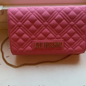 Moschino  - Fin äkta väska present från Raglady. Rosa härlig färg.  Höjd: 13.5 cm i storlek One Size Längd: 22 cm i storlek One Size Vidd: 6 cm i storlek One Size Handtag: 54 cm i storlek One Size