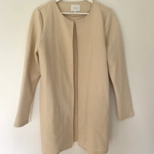 Helt ny sommarjacka från Vila/ stl: L - Helt ny sommarkappa från Vila i storlek L. Säljes då den tyvärr är fel storlek för mig. Jackan är beige och gjord i ett mjukt tyg som är stretchigt. På sista bilden visas passformen på jackan. Färgen är slutsåld i butik och online. :)