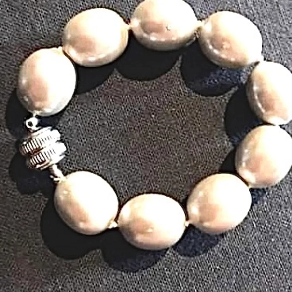 Armband m vita pärlor , 1.2 cm i diameter. Armbandet knäpps m magnetlås. Accessoarer.