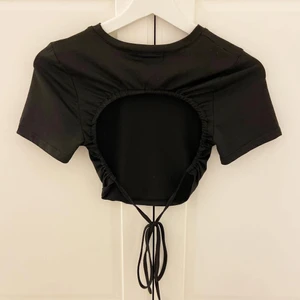 Topp med öppenrygg  - Svart topp med öppenrygg och knytning. Väldigt skönt material! Oanvänd.