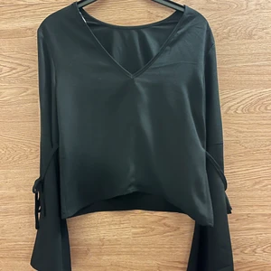 Svart blus från Nelly  - En svart blus i 100 polyester från Nelly! Vida ärmar med knyte. Även en liten djupare V-ringning i ryggen som är en fin detalj! ✨