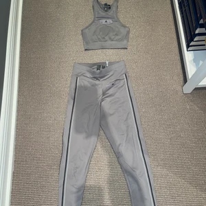 Träningssett - Ett grått träningssett ifrån Stella McCartney Adidas bestående av ett par träningstights och en träningstopp i väldigt bra skick. Köptes för ungefär 2 år sedan men knappt använt!