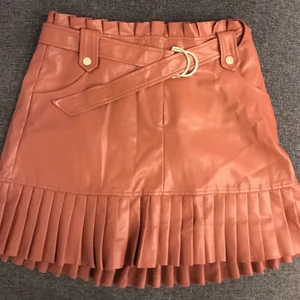 Rostrosa ”skinnkjol” i stl L - En rostrosa skinnkjol med skärp i midjan i stl L. Den är gott skick och är ifrån Zara! 