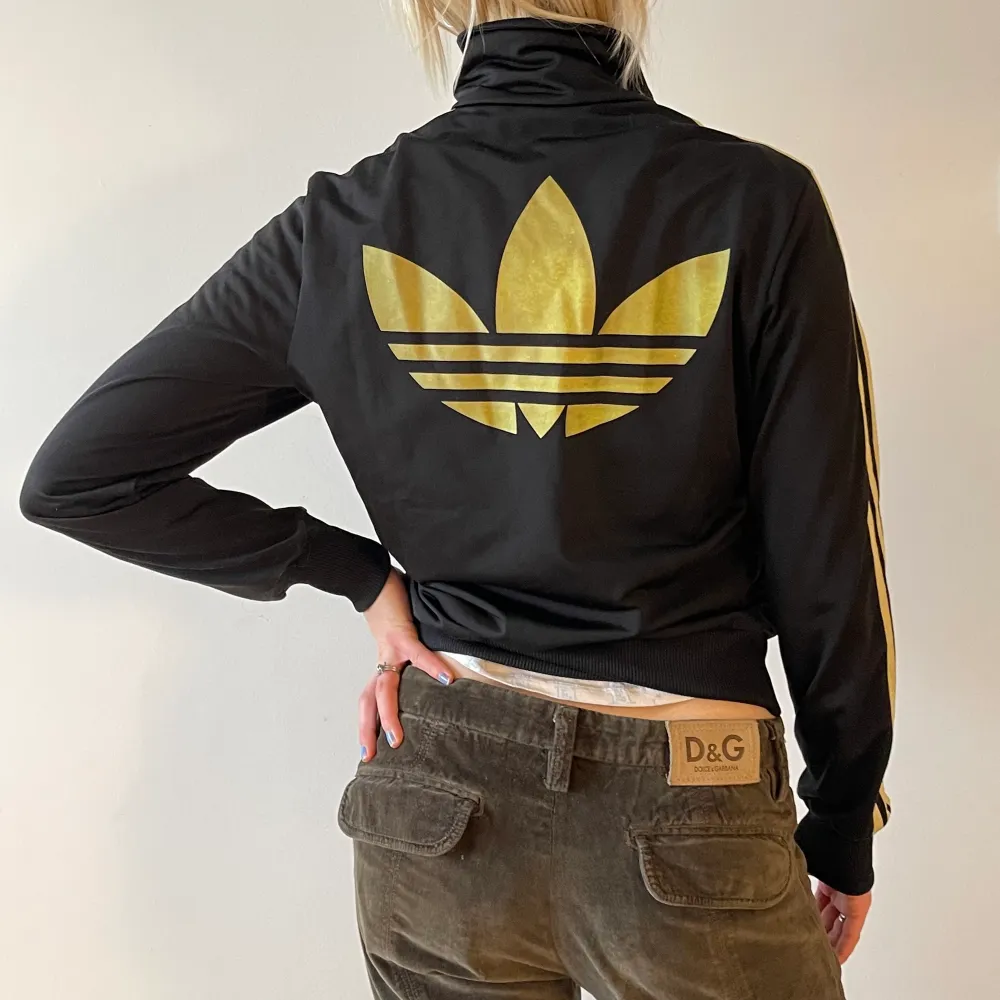 Adidaströja med dragkedja. Guldiga detaljer och stor logga på ryggen.. Hoodies.