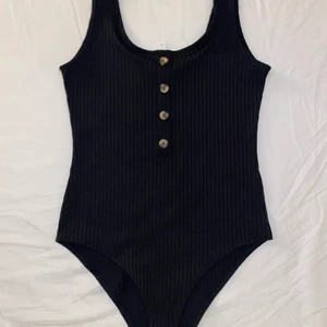 Ribbad body med knappar - Hej säljer nu min svarta body som är i nyskick, endast använd 1 gång. Säljer då den inte längre är min smak. Passar till allt så som jeans, kjol, mjukisar.   Bara att skriva vid frågor eller intresse ☺️