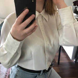 Vintage Vit Skjorta - ”Blus”-skjorta i mycket fint skick med söta knapp- och kragdetaljer. Köpt second hand. Tyg av hög kvalitet som faller fint och inte skrynklar sig. Säljer då jag har fler liknande plagg. Kan mötas i Uppsala eller skicka (frakt 48kr + 10kr kostnadstillägg om SafePay önskas). Se min profil för fler fina plagg.