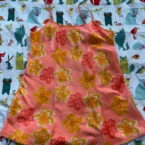 Blommig klänning - Säljer min orangea klänning med blommor i glansigt material. Den framhäver verkligen ens bränna på sommaren