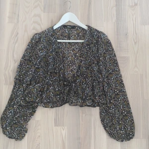 En  - Säljer en blommig blus med knyte, inte använd mycket alls 