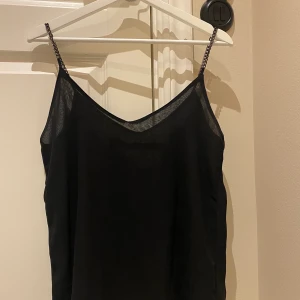 Svart topp - En svart topp med kedjor som axelband från lager 157. Kan skickas om köpare står för frakt