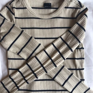 Randig tröja - En beige och mörkblå randig tröja som sitter längs kroppen!