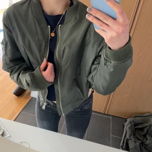 Bomberjacka  - Säljer denna ursnygga bomberjacka i den perfekta oliv gröna färgen! Orange insida som gör den extra ball! Perfekt till våren och sommaren, men kommer inte till användning längre. Det finns inga tecken på tidigare användning. Den är i storlek M men passar mindre också beroende på hur man vill att den ska sitta! Jag är 176!