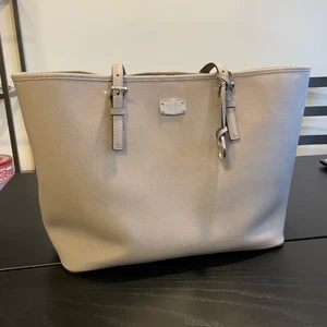 Michael Kors - shopping bag - Säljer min nästan oanvända MK shoppingbag. Den har för det mesta stått i ett skåp för att det är inte riktigt min stil. Väskan är äkta, finns QR kod inuti som man nog kan gå till en butik och få bekräftat. Färgen är ljusgrå och storleken är large. 