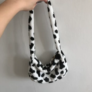 Komönstrad handväska - En fluffig handväska i komönster endast använd en gång på halloween så den är som ny!!🐮
