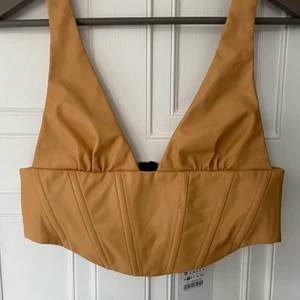 Topp i fake skinn.  - Beige topp, litet märke på framsida, se bild. Nyskick, oanvänd. 