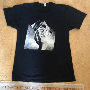 American Apparel tshirt - Tisha från American Apparel, köpt second hand, med coolt tryck på framsidan. Flera år gammal så säljer billigt. Möts upp i city eller södermalm, frakt går att fixa.