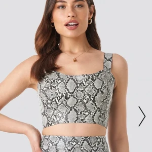 Topp - Croppad topp från Linn ahlborgs kollektion med nakd. Köptes för 300kr. Slutsåld på nakds hemsida. Snake print i PU. Frakt på 45 kr tillkommer men pris kan diskuteras vid snabb affär. Använd en gång. Dragkedja baktill.
