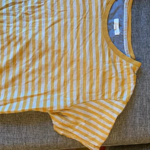 Gul/beige-randig t-shirt - Randig t-shirt i beige och gult. Strl L funkar även bra för M. Tunnt fint material. Köpare betalar frakten. 