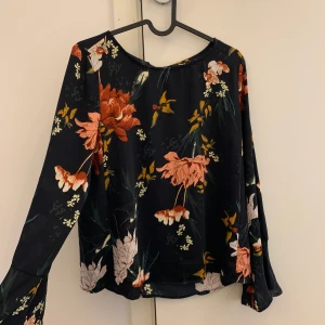 Blommig blus - Fin blommig blus med vid ärmslut och knyte bak. I nyskick.