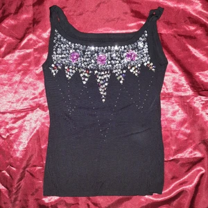 Linne med pärlor och paljetter - Underbart glittrigt linne med paljetter och pärlor bland annat i form av fjärilar och blommor. Bra skick, materialet är mycket stretchigt. Okänt märke. Kan hämtas i Stockholm, annars står köpare för frakten :)